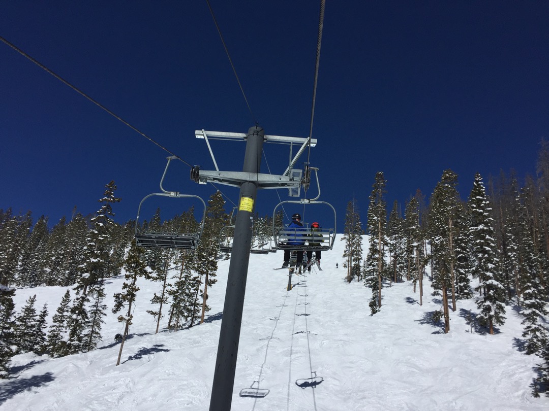Tim and Dad ride the Mary Jane lift under super blue skies