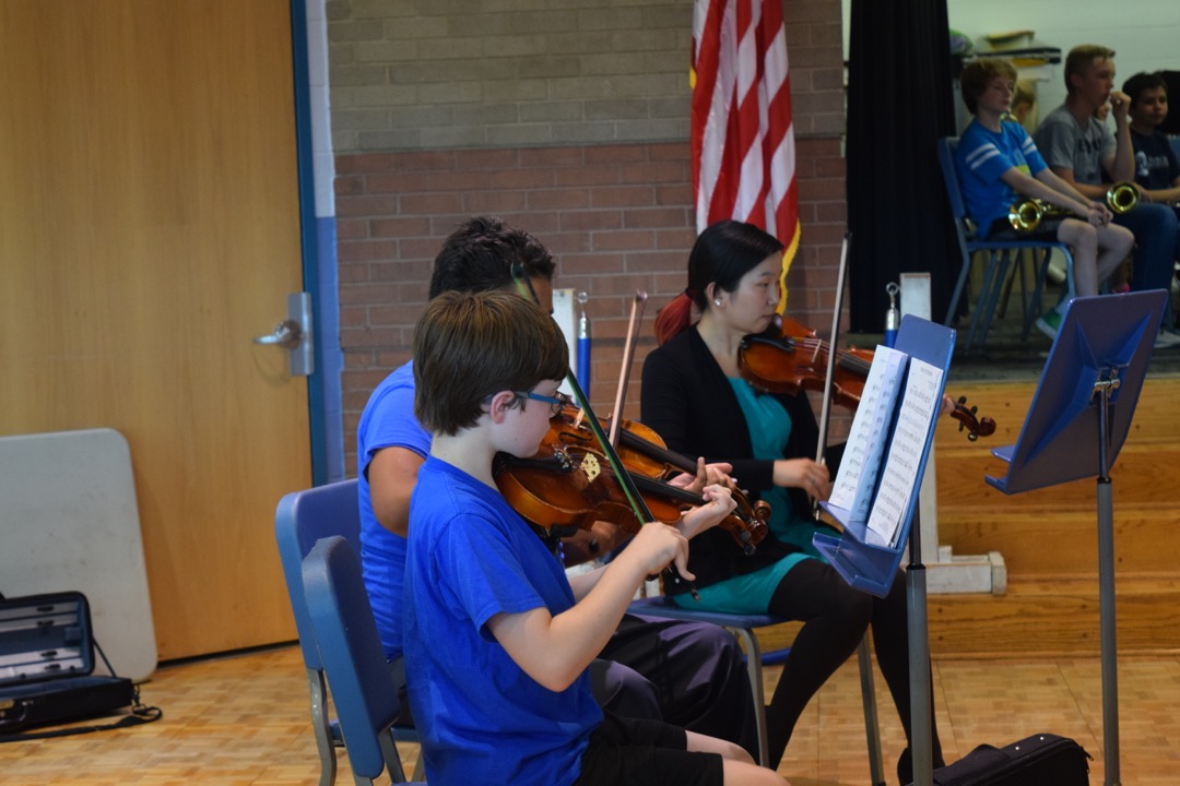 Orchestra plays while band looks on