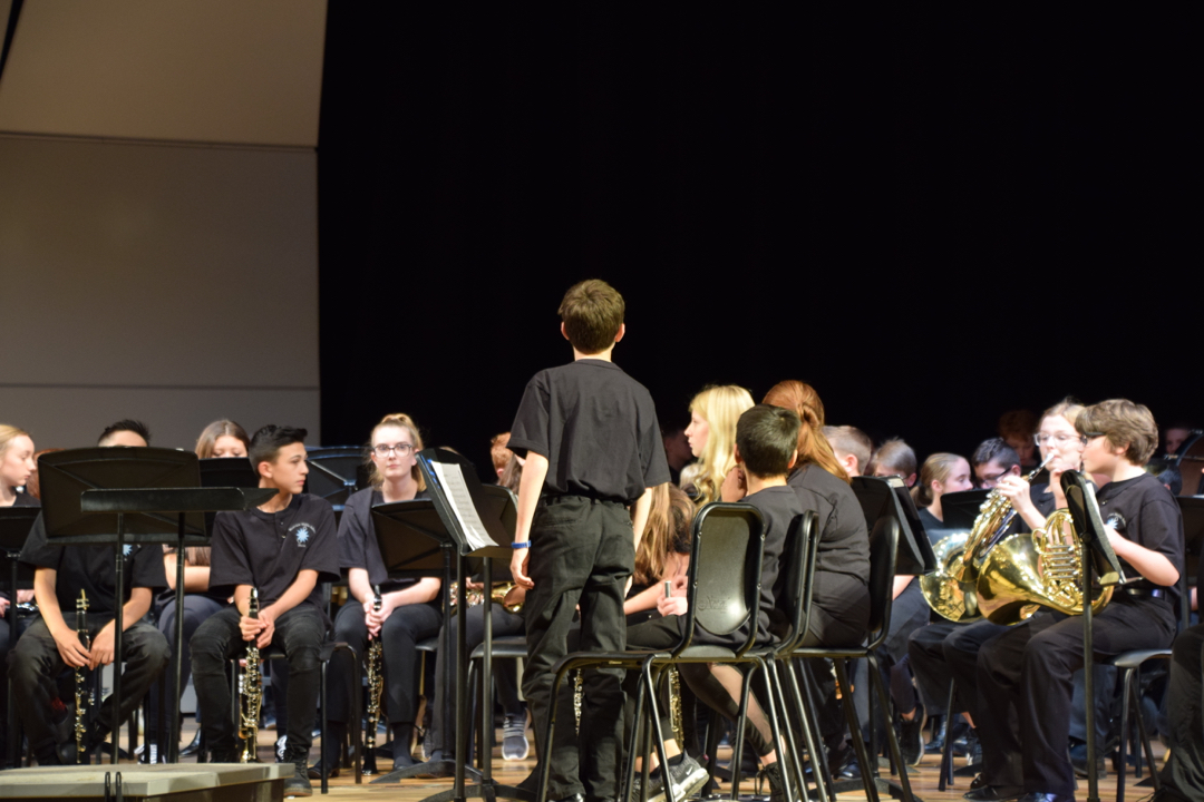 Ted, the Concert Master, alerts the 7th grade band that their teacher is entering the stage