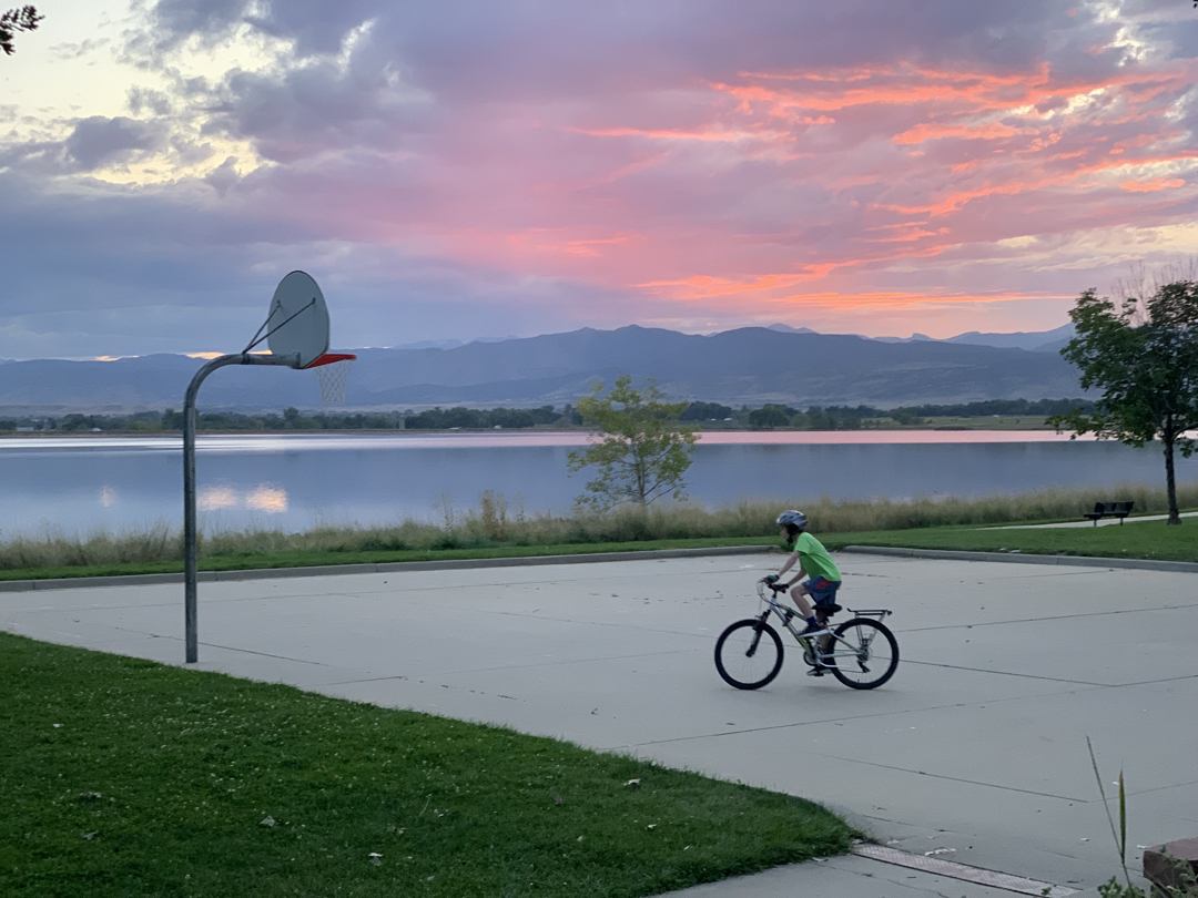 Ted rides his bike while the sun sets dramatically