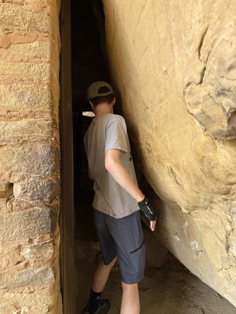 Ted squeezes through a passage at Balcony House
